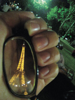 Photo: hand holding sunglasses with reflection of Eiffel Tower
