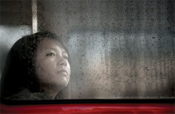 Photo: Student gazing out wet bus window
