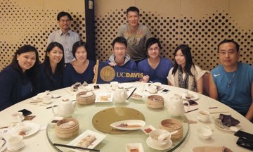 Photo: nine people at a table with Chinese food and a UC Davis pennant