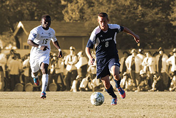Two soccer players chase the ball.