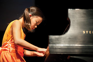 young girl plays a grand piano