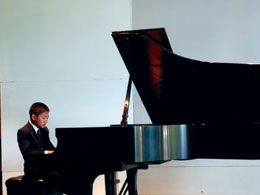 Photo: young boy dressed in suit plays piano