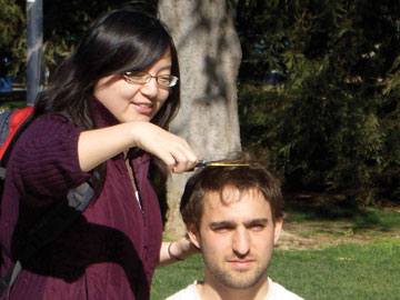 Photo: young woman cuts a snip of Tommy Anker's hair