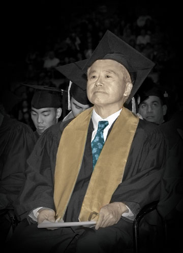 Photo: Bryan Eya in cap and gown, seated at commencement ceremony