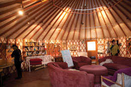 Photo: interior of yurt furnished with couches, chairs, bookshelves