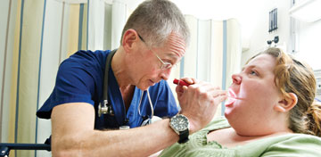 Photo: Doctor looking in female patient's throat
