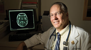 The scientist in front of a screen showing a brain scan
