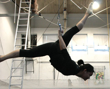 Photo: Toni Alejandria hanging upside down from trapeze, legs in splits