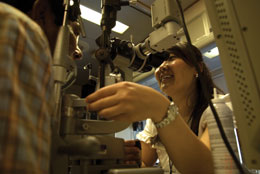 Photo: Annie Baik looking through scope at patient's eyes 