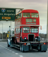 Photo: Truck carrying double-decker bus on freeway, under sign for I-5 South, Los Angeles