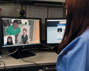 Photo: Health care provider talks via video conference with a doctor and his patient, a young boy
