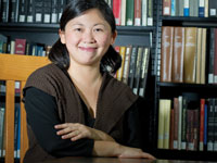 Photo: the novelist sitting, smiling, in front of a bookcase