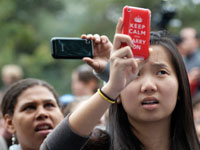 Photo: Female student recording rally on phone, which has skin that reads "Keep Calm and Carry On" 